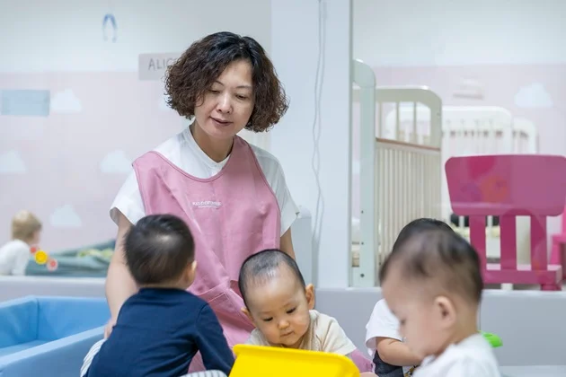 KiddiWinkie educator with infants in a bright infant care setting