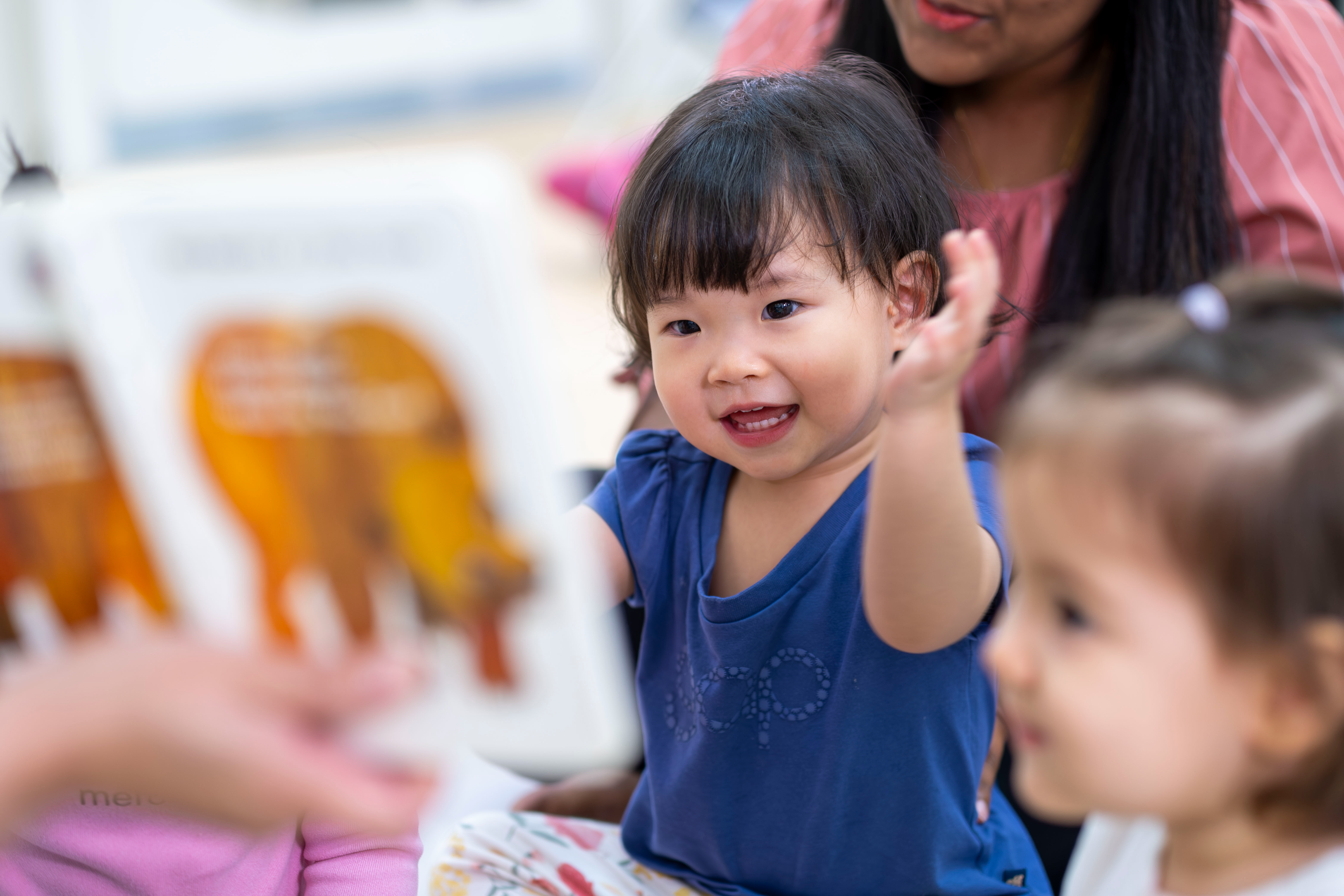 Young child looking at a picture book with an adult